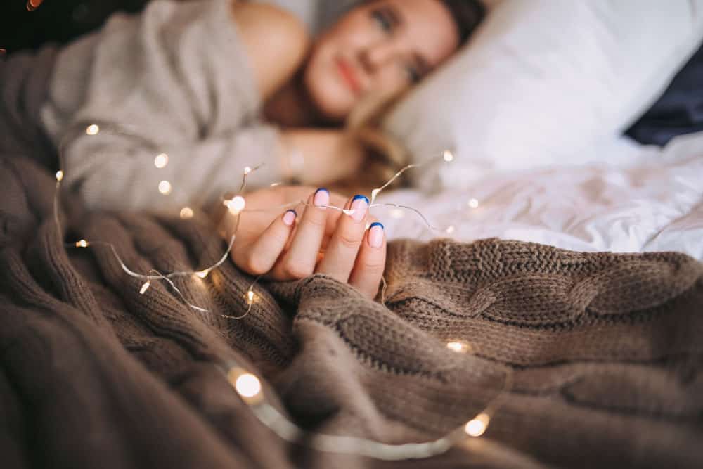 girl-sleeps-bed-morning-with-garland-her-hand-dreams