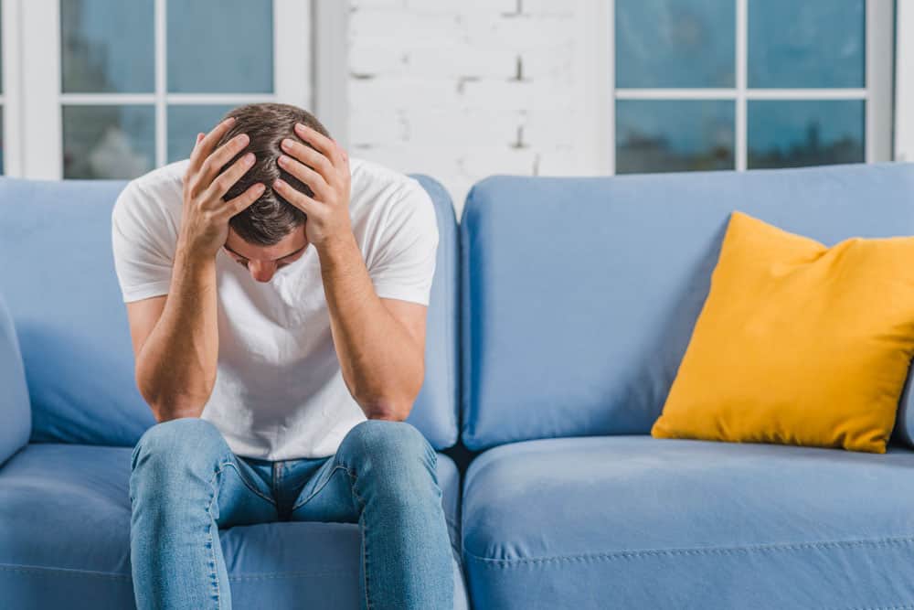 man-sitting-blue-sofa-suffering-from-headache