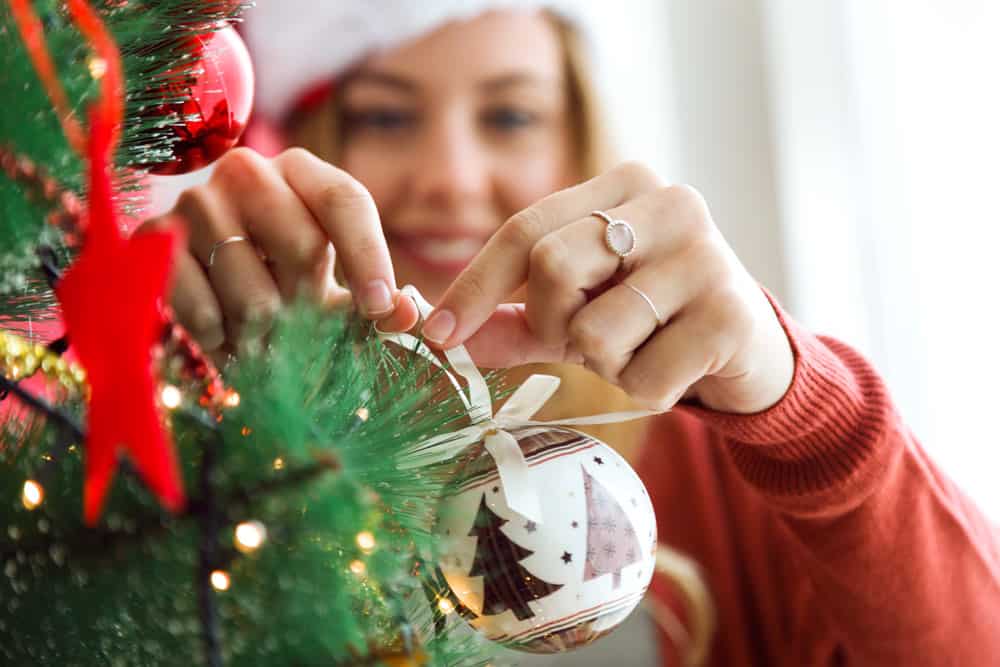 woman-decorating-christmas-tree-with-white-ball