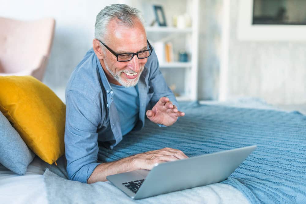 senior-man-on-bed-using-laptop