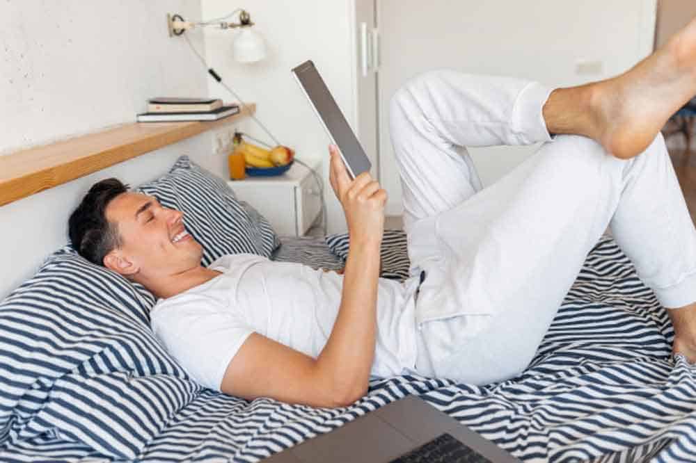 man reading tablet on bed