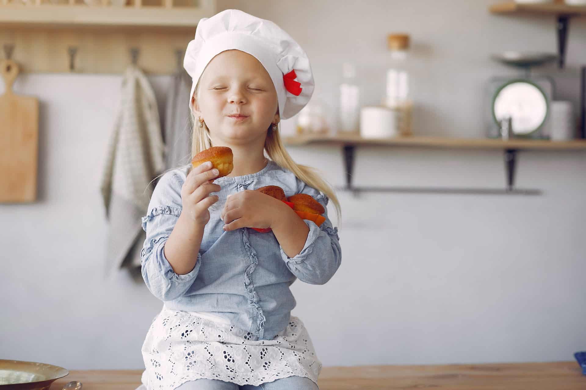 Little girl in a kitchen. Child with a cupcakes. Kid in a shef hat