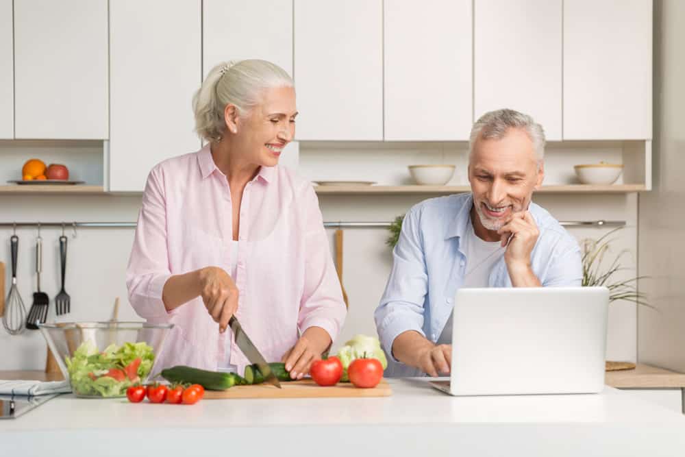 mature-loving-couple-family-using-laptop-cooking-salad