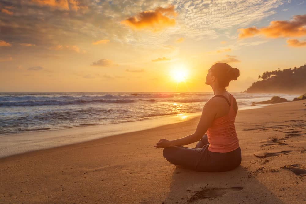 woman-doing-yoga-oudoors-beach-padmasana-lotus-pose