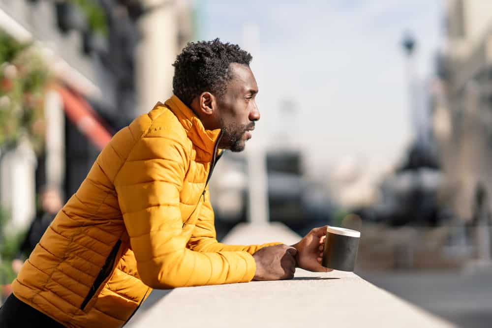 side-view-portrait-serious-african-man-leaning-balcony-holding-cup-coffee-contemplating-views-city