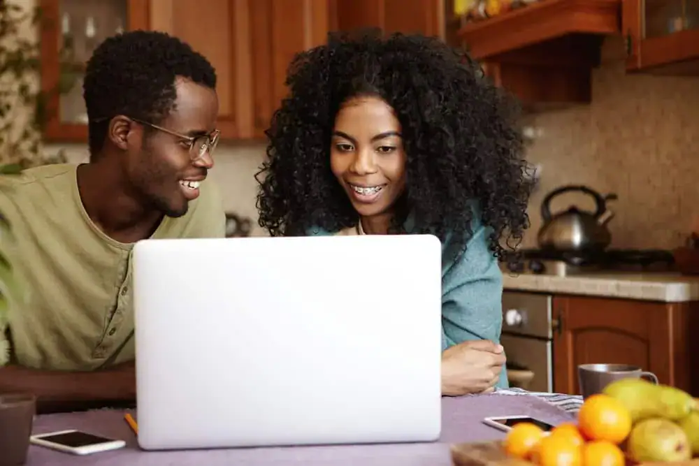 happy-young-afro-american-family-sitting-kitchen-table-surfing-internet-generic-laptop-pc-shopping-online-searching-home-appliances-people-modern-lifestyle-technology-concept happy-young-afro-american-family-sitting-kitchen-table-surfing-internet-generic-laptop-pc-shopping-online-searching-home-appliances-people-modern-lifestyle-technology-concept
