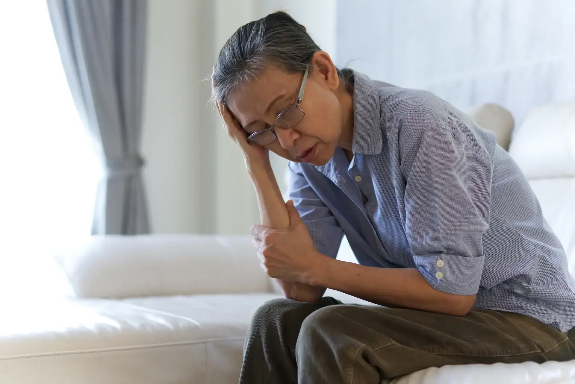 Mature woman sitting on a white sofa at home Mature woman sitting on a white sofa at home
