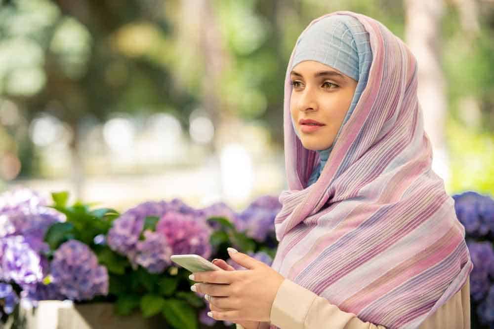 woman wearing hijab holding mobile woman wearing hijab holding mobile